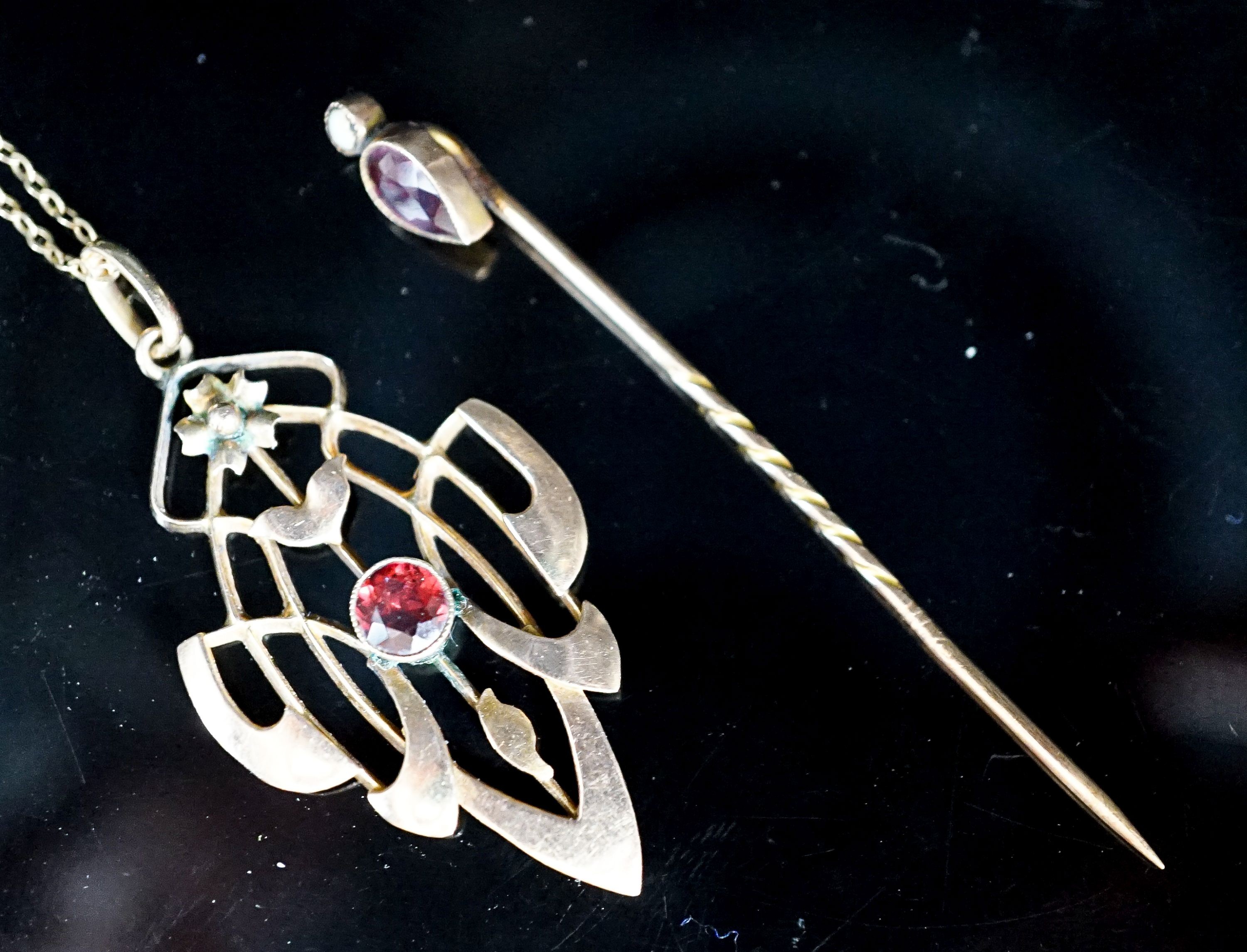 An Art Nouveau yellow metal and garnet set pendant,39mm, on a 9ct chain and a garnet and split pearl set stick pin, gross weight 5.8 grams.